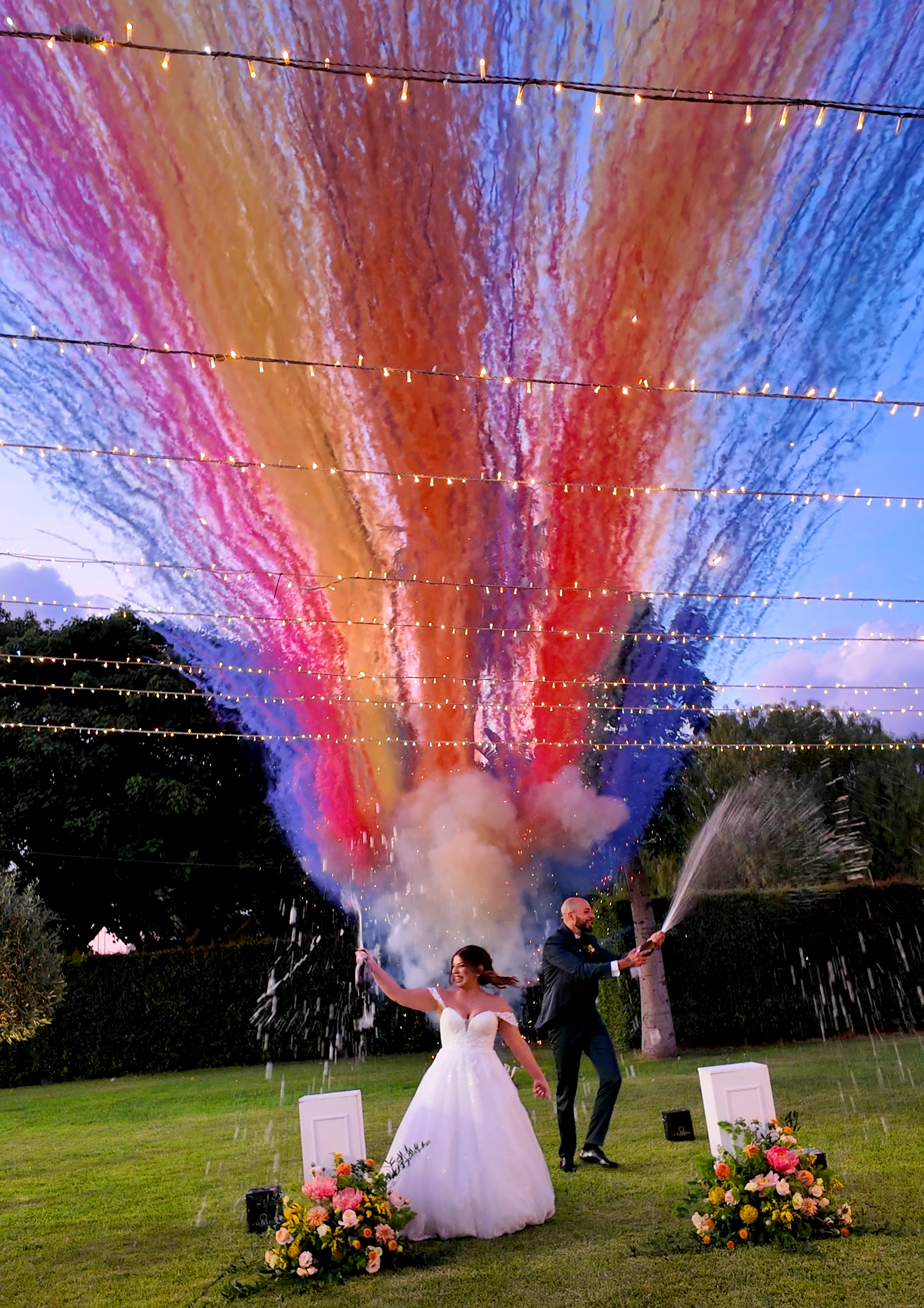 Sposi che festeggiano tra fumogeni colorati sul prato della villa